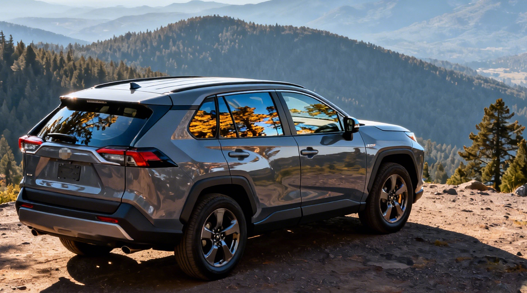 Rear three-quarter view of a car parked on a mountain overlook, with forested hills and distant mountains reflected in the windows, highlighting its rugged SUV design and outdoor-ready stance