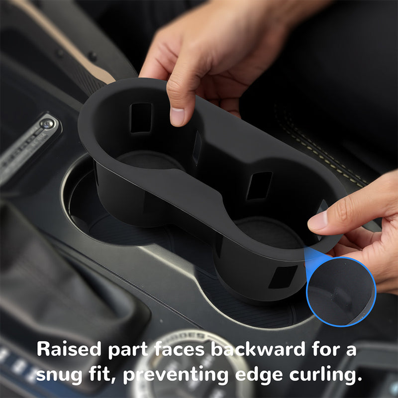 Two hands installing the silicone cup holder into a Ford console, highlighting the "raised part faces backward" for a snug fit and to prevent edge curling.
